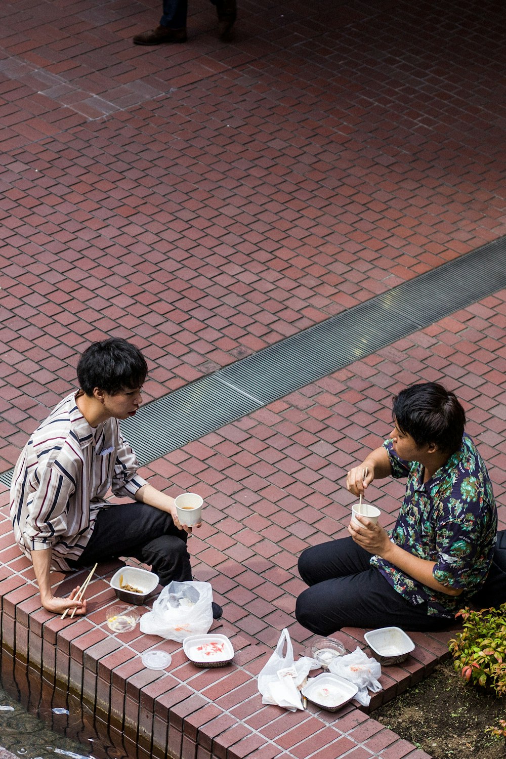 two men sitting on reddish brown concrete corner