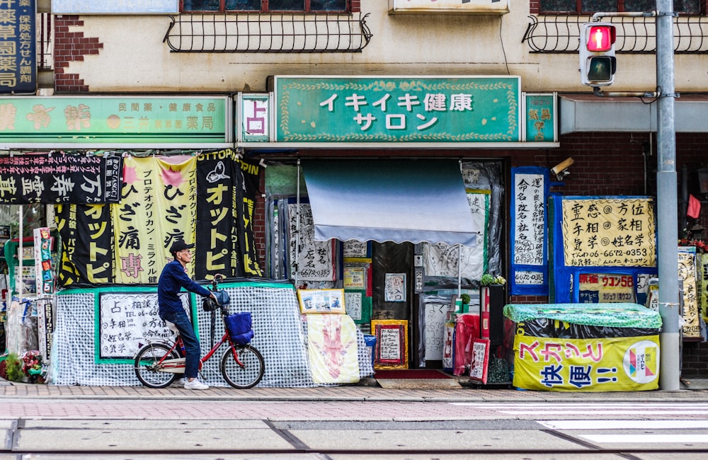 man riding red folding bike parked beside blue and white store