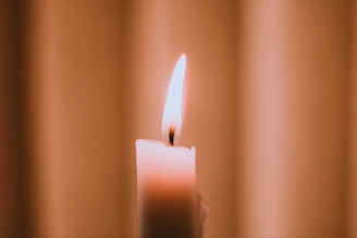 A gentle candle flickering softly against a calm, muted blue background symbolizing peace and reflection.