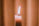 A soft-focus photo of a gentle candle flame flickering against a muted blue background.
