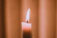 A softly lit candle flickering gently against a dark, serene background.