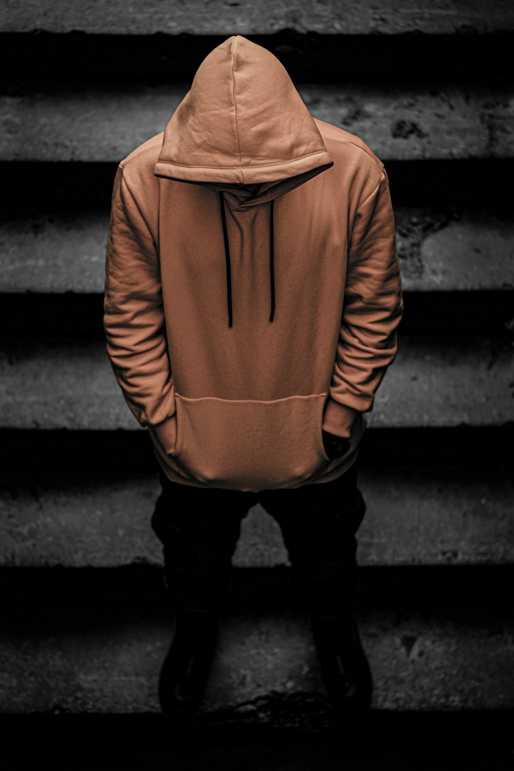 person in brown hoodie and black pants standing on staircase