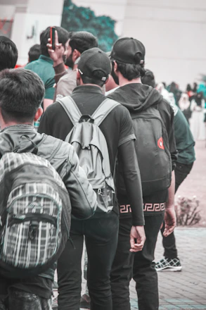 A diverse group of students smiling together on a university campus, holding books and backpacks.