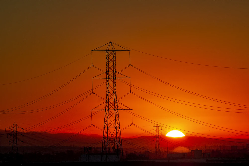 High-voltage transmission towers running to the horizon at golden hour