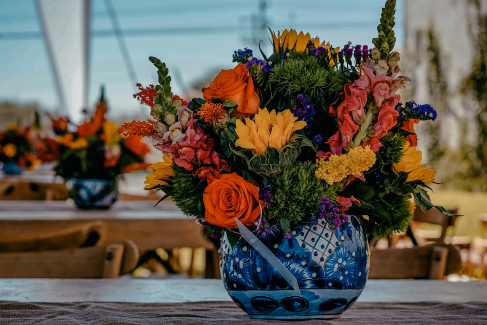 yellow, orange, and pink flower arrangement in blue floral vase