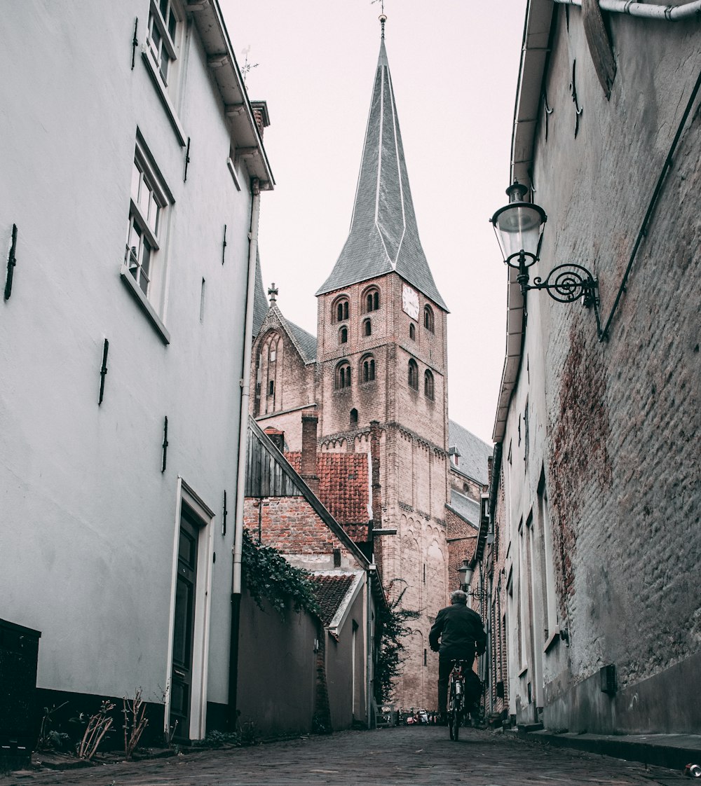 man biking on road viewing St Nicholas Church, Deventer in Netherlands