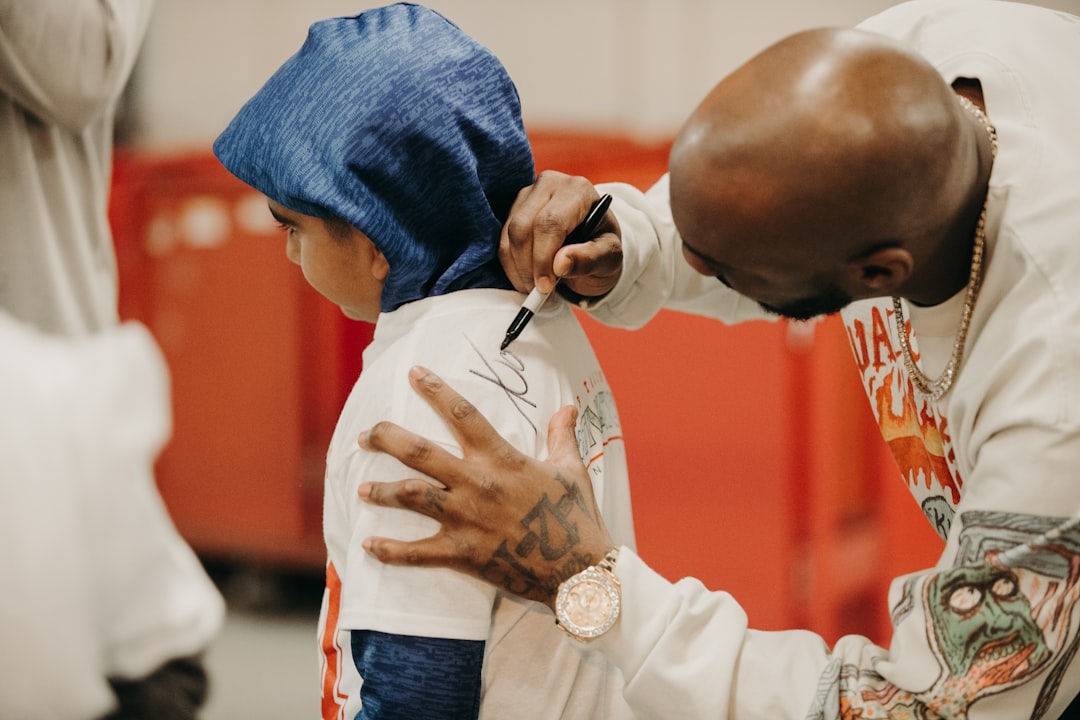 man writing on boy's back shirt