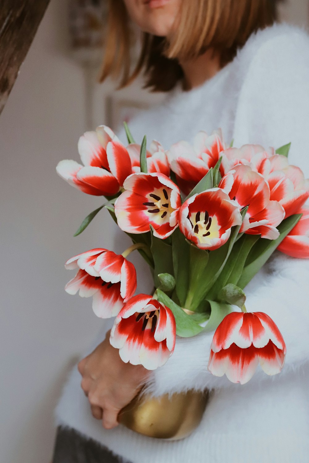 a woman holding a bouquet of red and white tulips