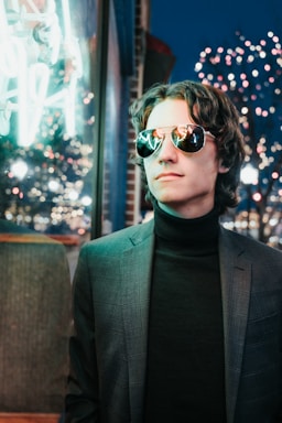 Close-up of a model wearing a rich charcoal flannel shirt layered over a black tee, set against an urban nighttime backdrop.