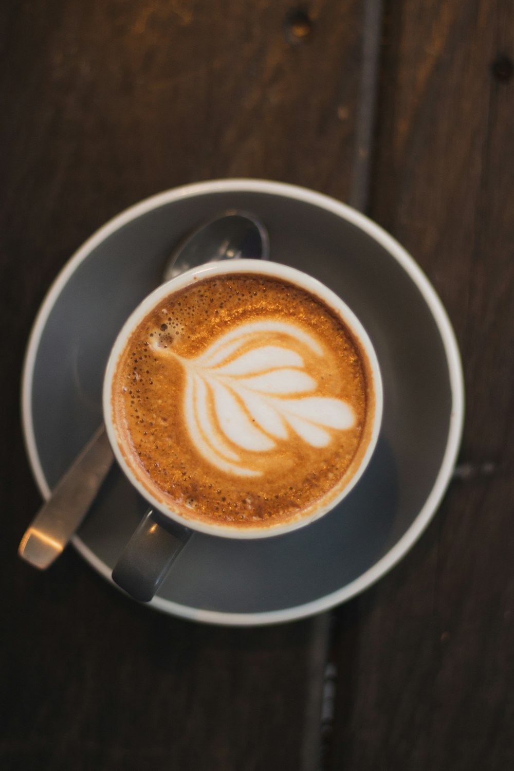 cappuccino in gray ceramic mug near teaspoon