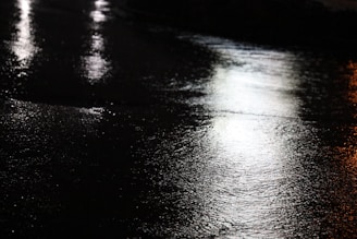 Reflective microbeads embedded in road paint shining under vehicle headlights at night.
