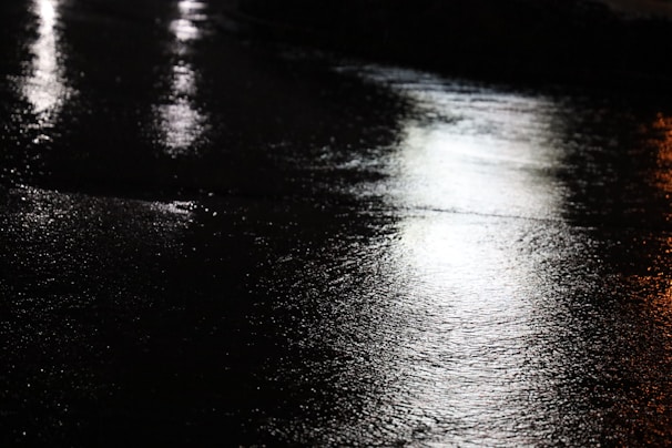 Reflective microbeads embedded in road paint shining under vehicle headlights at night.