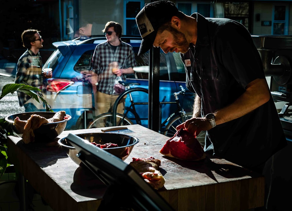 man touching slice of meat beside bowl of meat slices