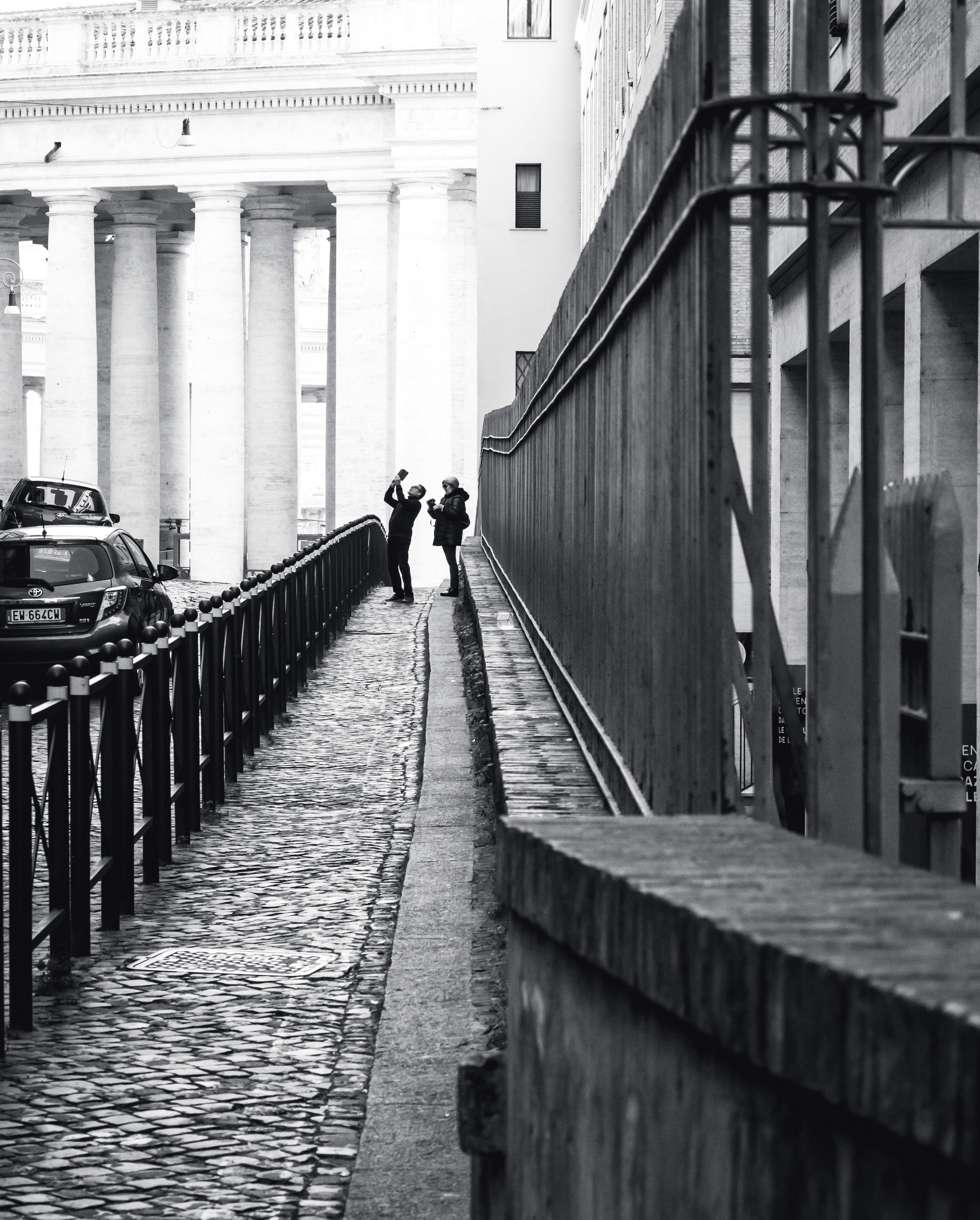 Grayscale photography of two people standing near railings beside ...
