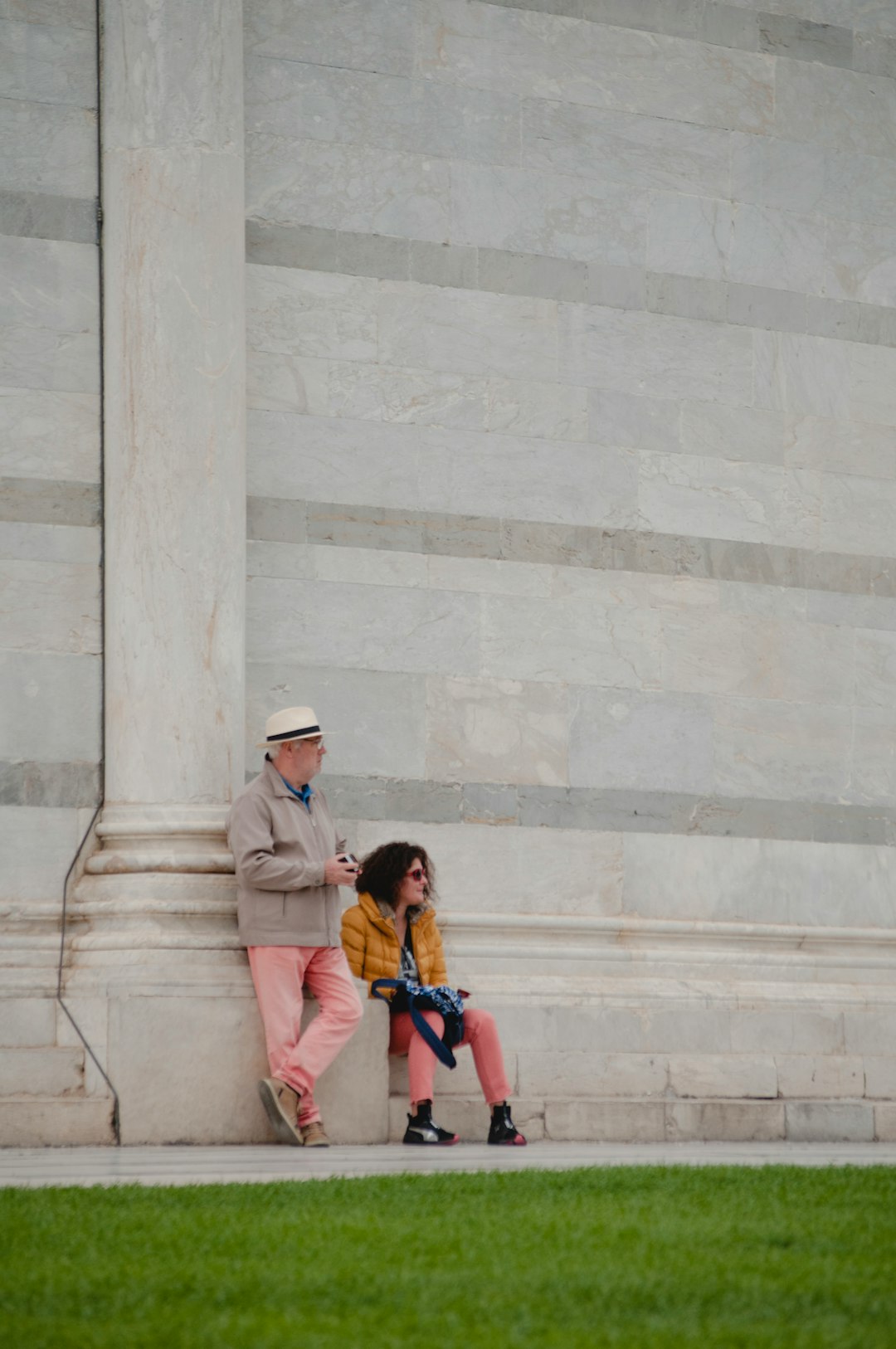 woman sitting on concrete pavement near man standing