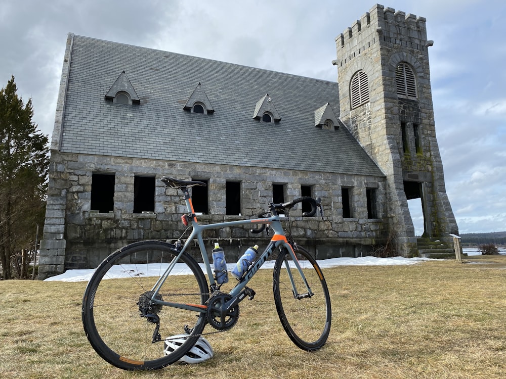 bicicleta de estrada estacionada na grama perto do edifício com torre durante o dia