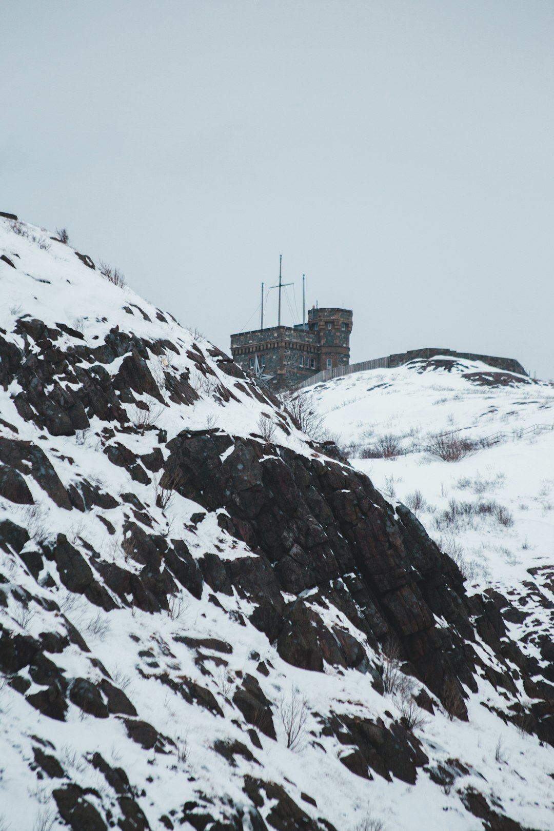 cliff and building covered with snow during daytime