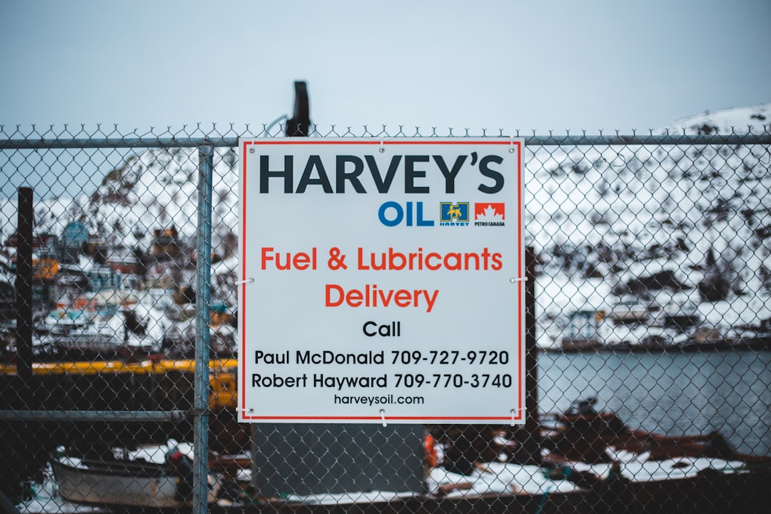 Harvey's Oil fuel & lubricants delivery call Paul McDonald 709-727-9720 sign on chain link fence during winter and day