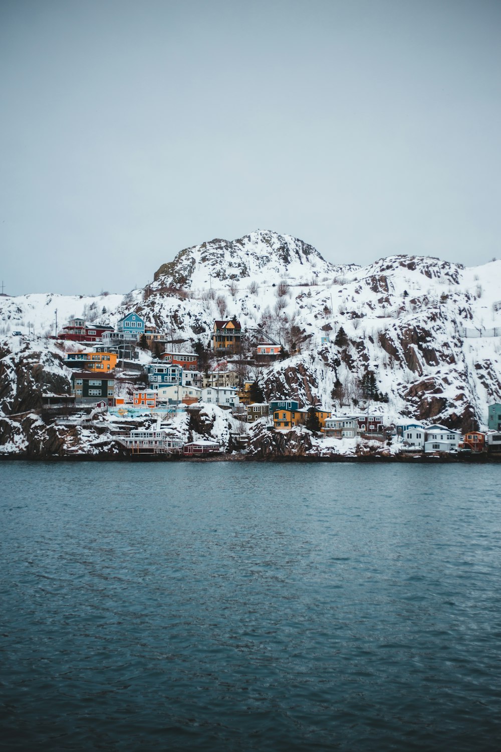 houses on cliff viewing body of water during daytime