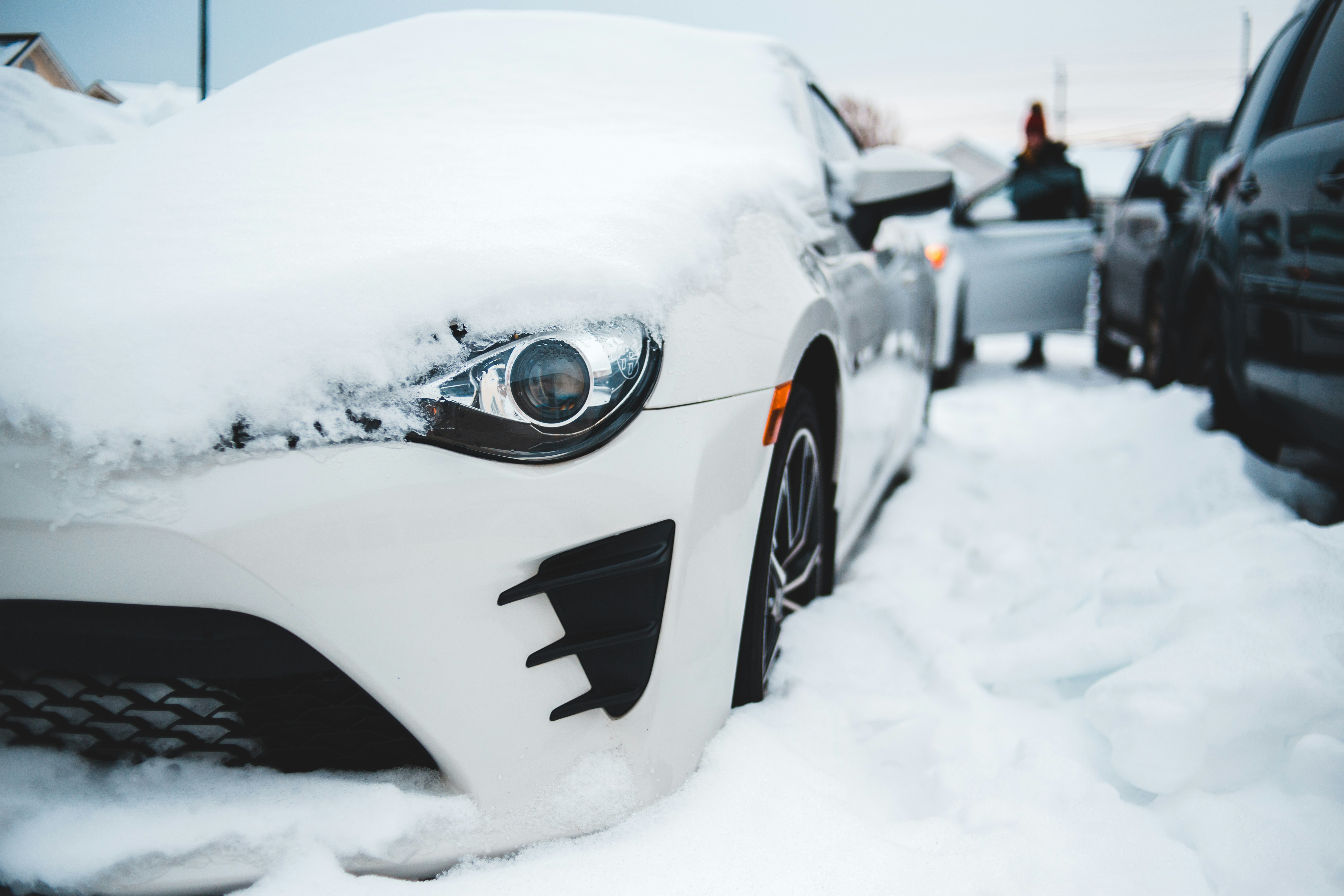 Electric vehicle plugged in and charging outdoors during winter snow