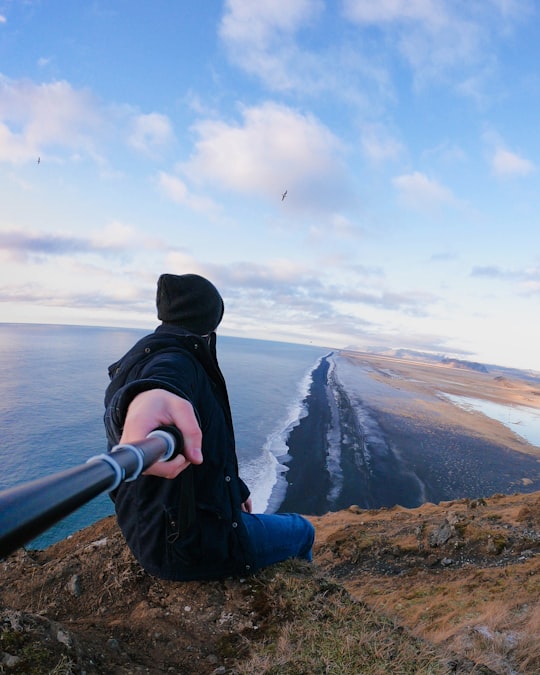 person sitting on the mountain cliff in Vik Iceland