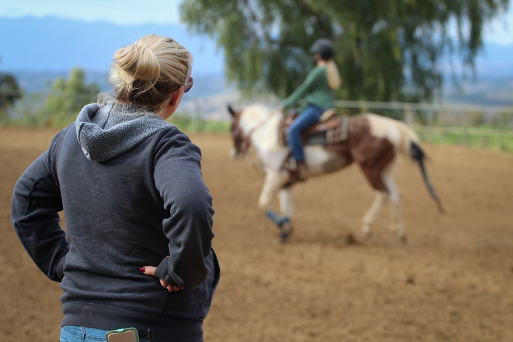 woman watching man riding horse