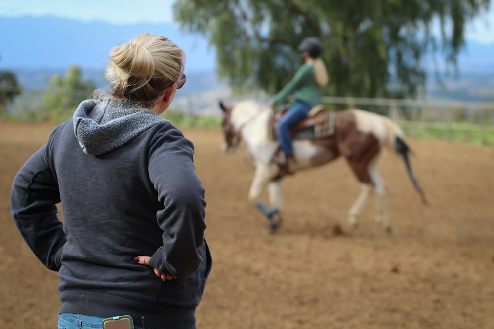 Mujer mirando al hombre montando a caballo