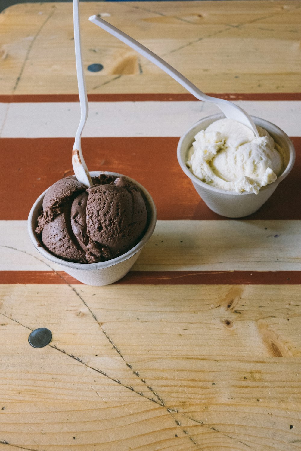 two white plastic cups filled with ice creams