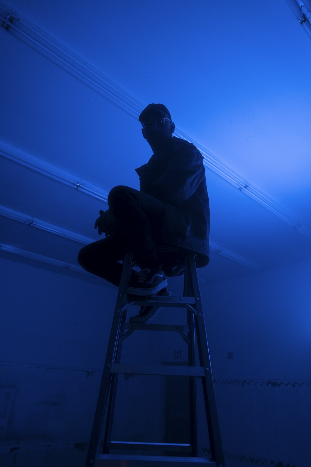 man sitting on top of A-frame ladder