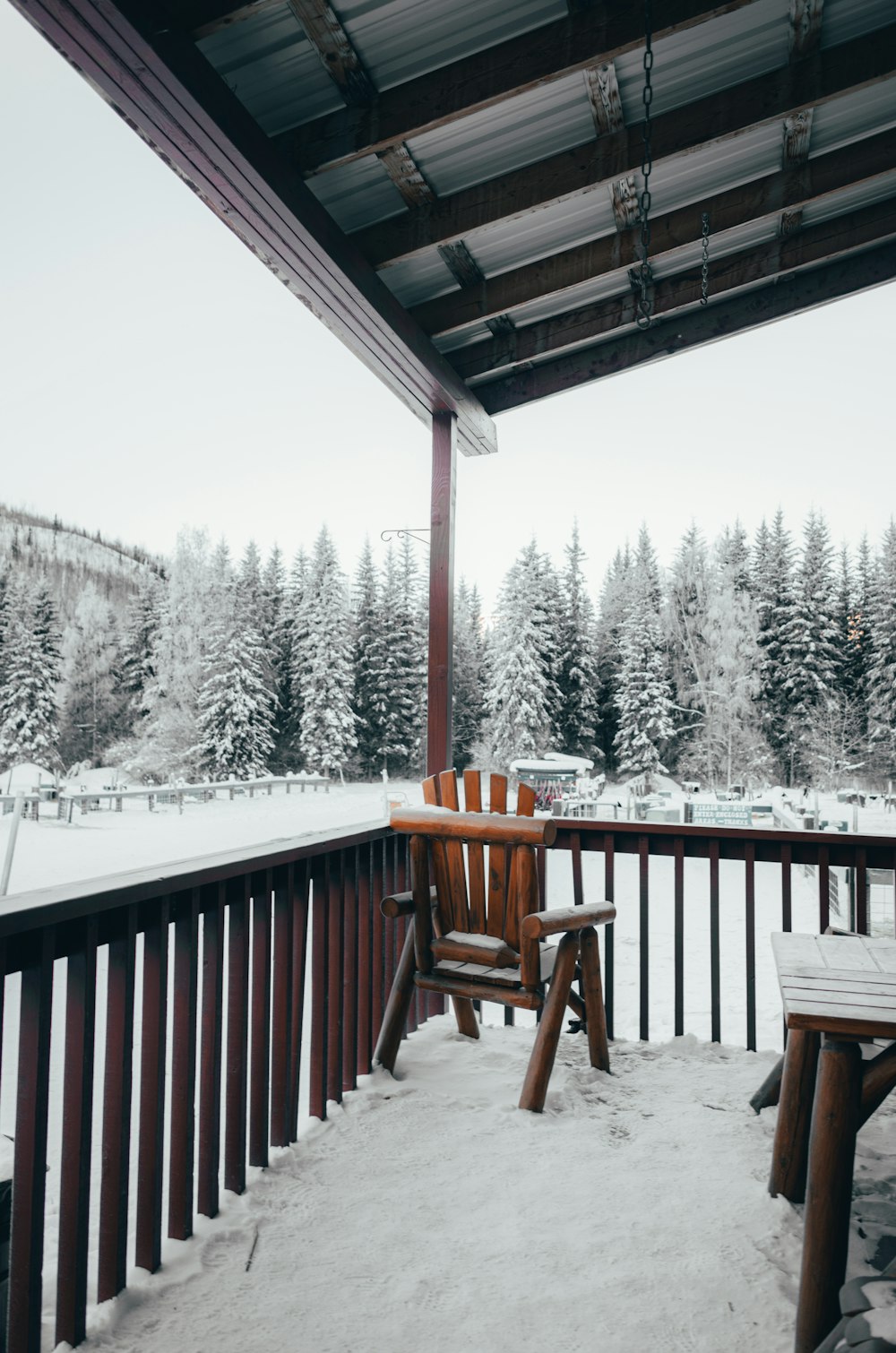 brown wooden chair and chair on balcony and field and vehicles covered with snow during daytime
