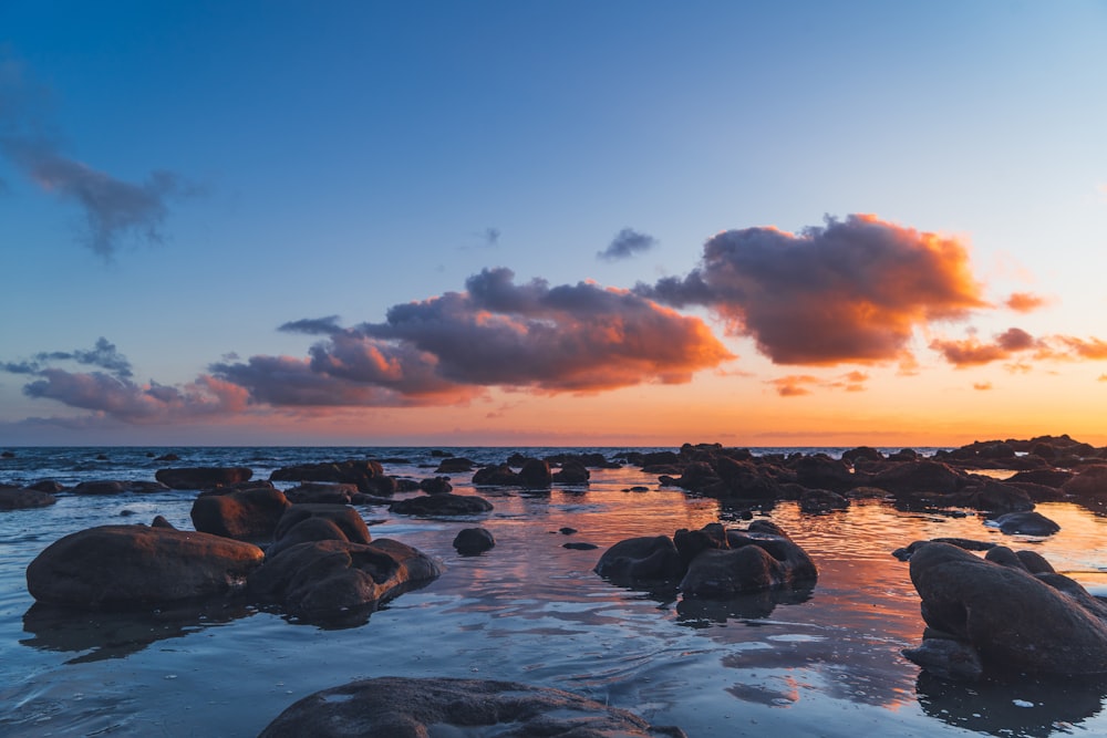 boulders in sea during golden hour