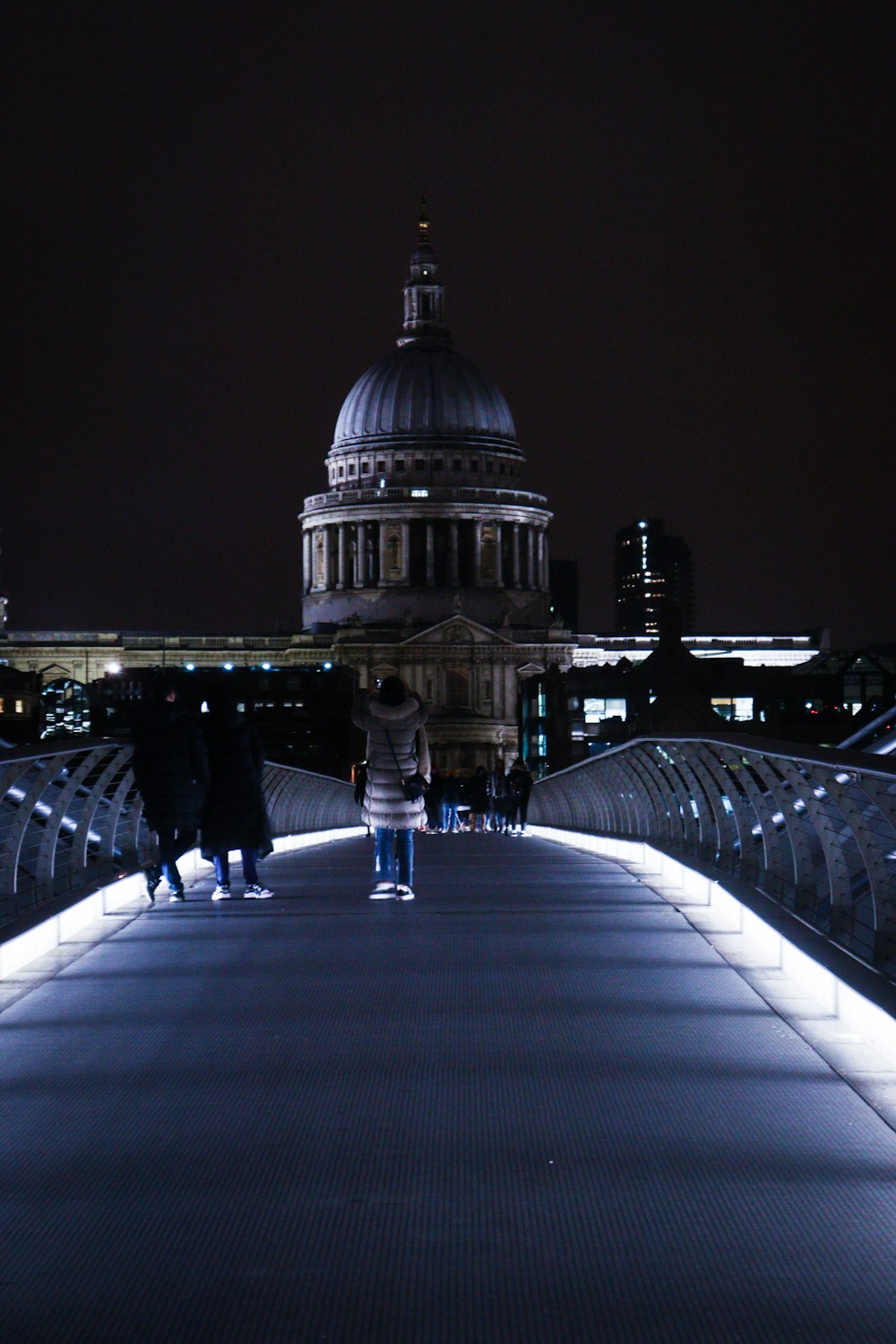 two people walking across a bridge at night