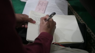 A close-up of a person reviewing a traffic ticket with a pen and notepad.