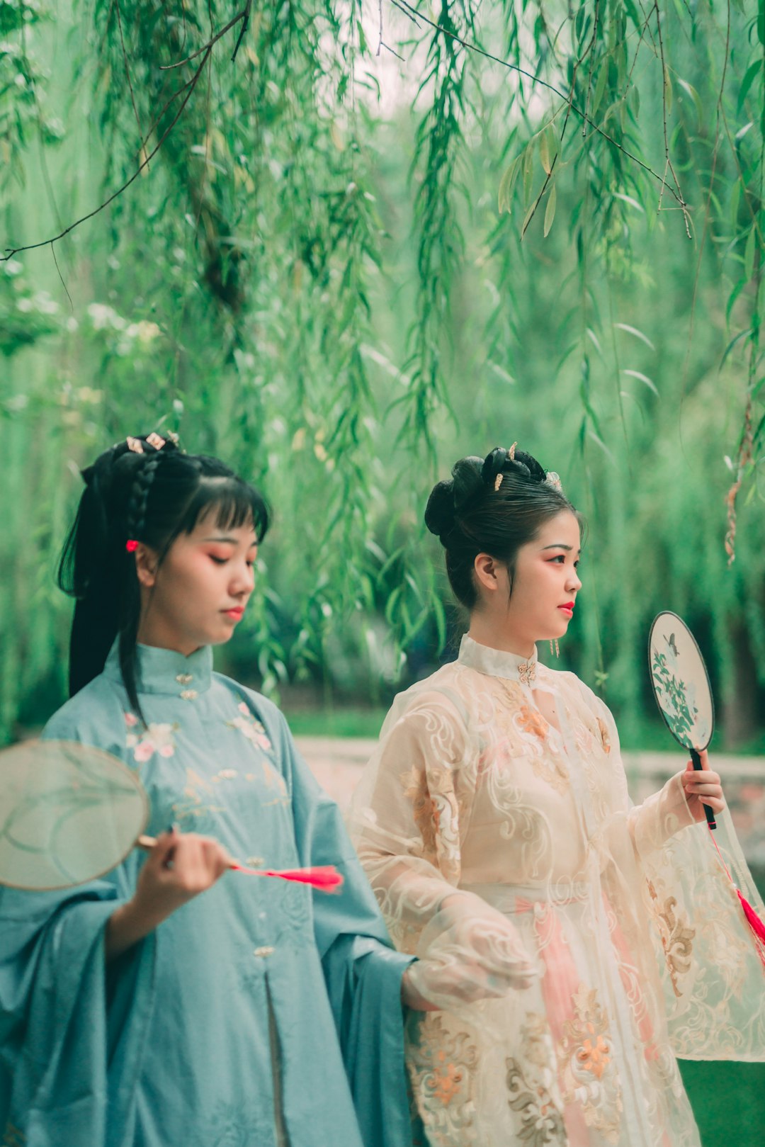 two women wearing traditional dresses beside trees during daytime
