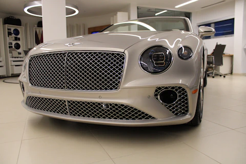 A sleek luxury sedan gleaming under soft natural light in a minimalist showroom.