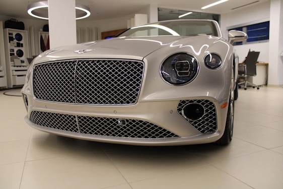 A sleek luxury car gleaming under soft showroom lighting, highlighting its flawless design and craftsmanship.