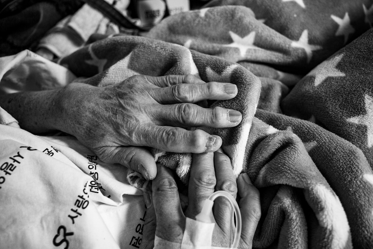 Mains d'une personne âgée sur un lit d'hôpital