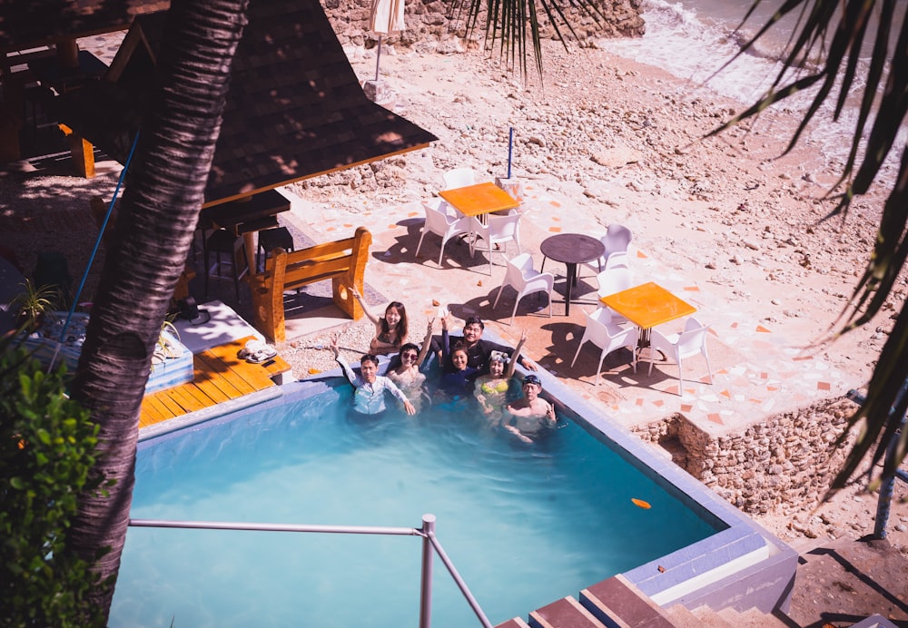 a group of people standing next to a swimming pool