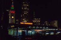 Close-up of hands signing mortgage documents with a San Francisco skyline visible through the window.