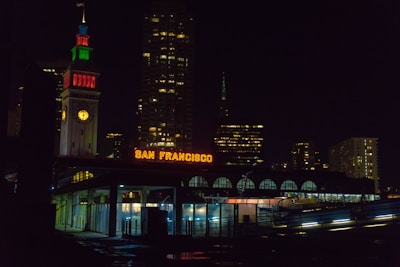 Close-up of hands signing mortgage documents with a San Francisco skyline visible through the window.