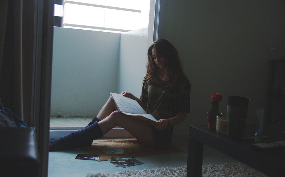 a woman sitting on the floor reading a book