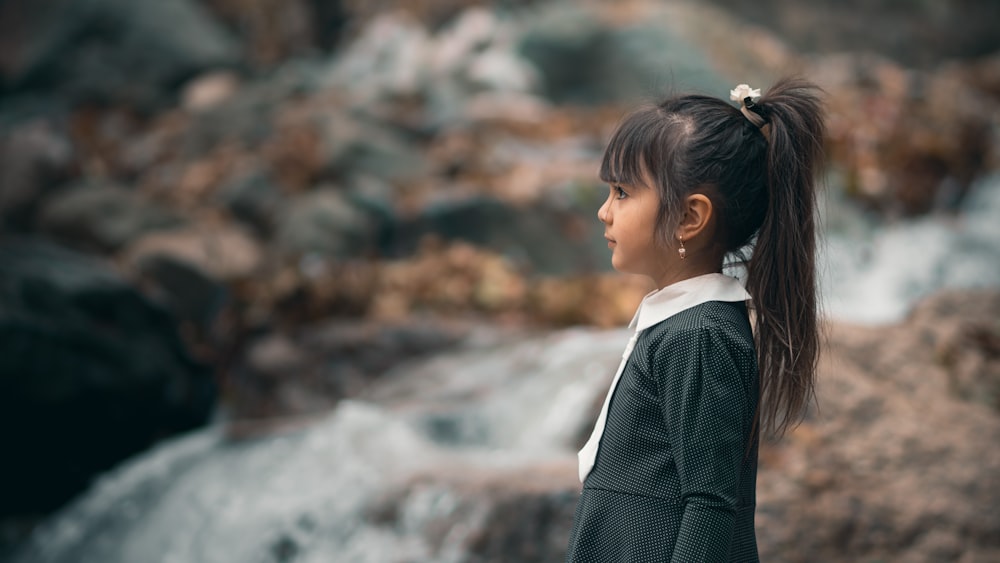 girl in ponytail and black dress near waterfall