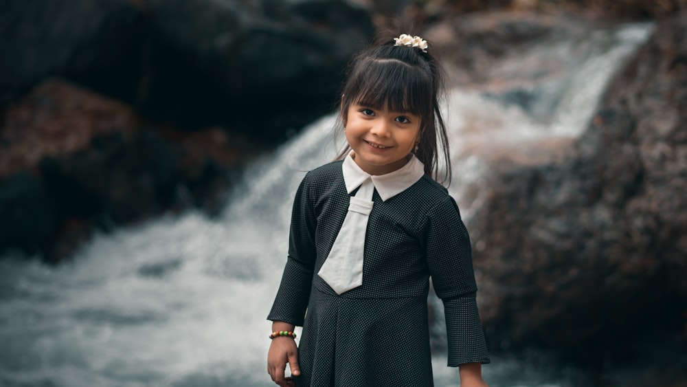 a young girl standing in front of a waterfall