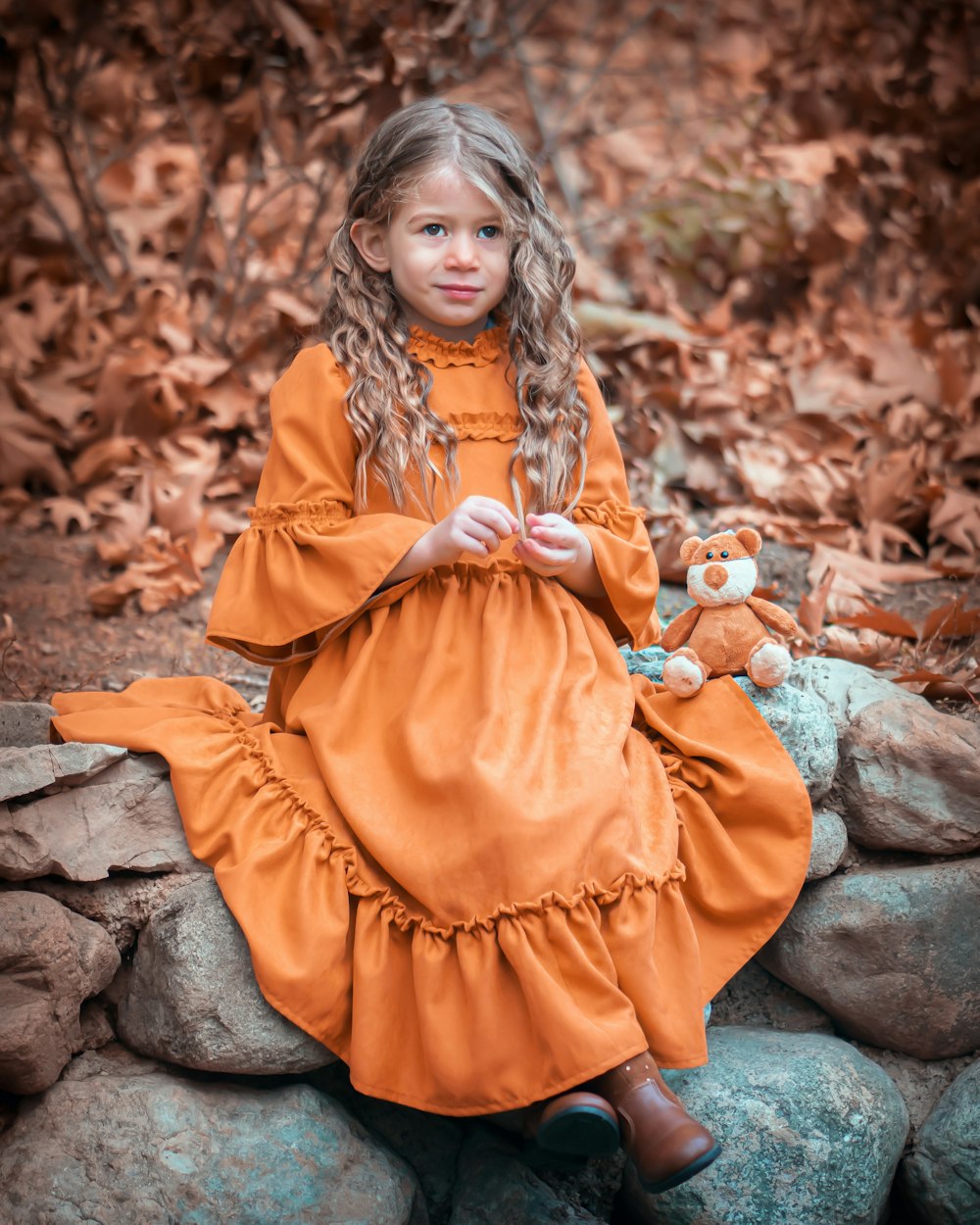 girl wearing orange dress sitting on rocks