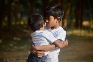Two children hugging their plush guardian angels in a park.