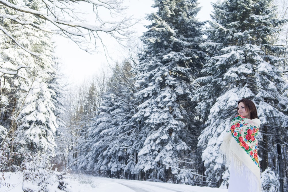 woman wearing white and red floral dress standing near the trees