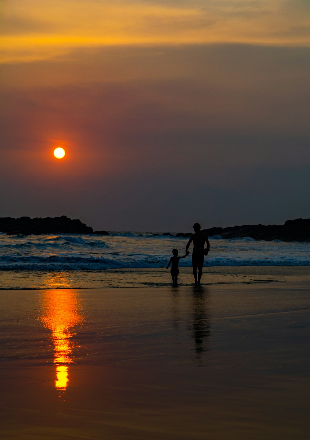 man and child walking on seashore during golden hour