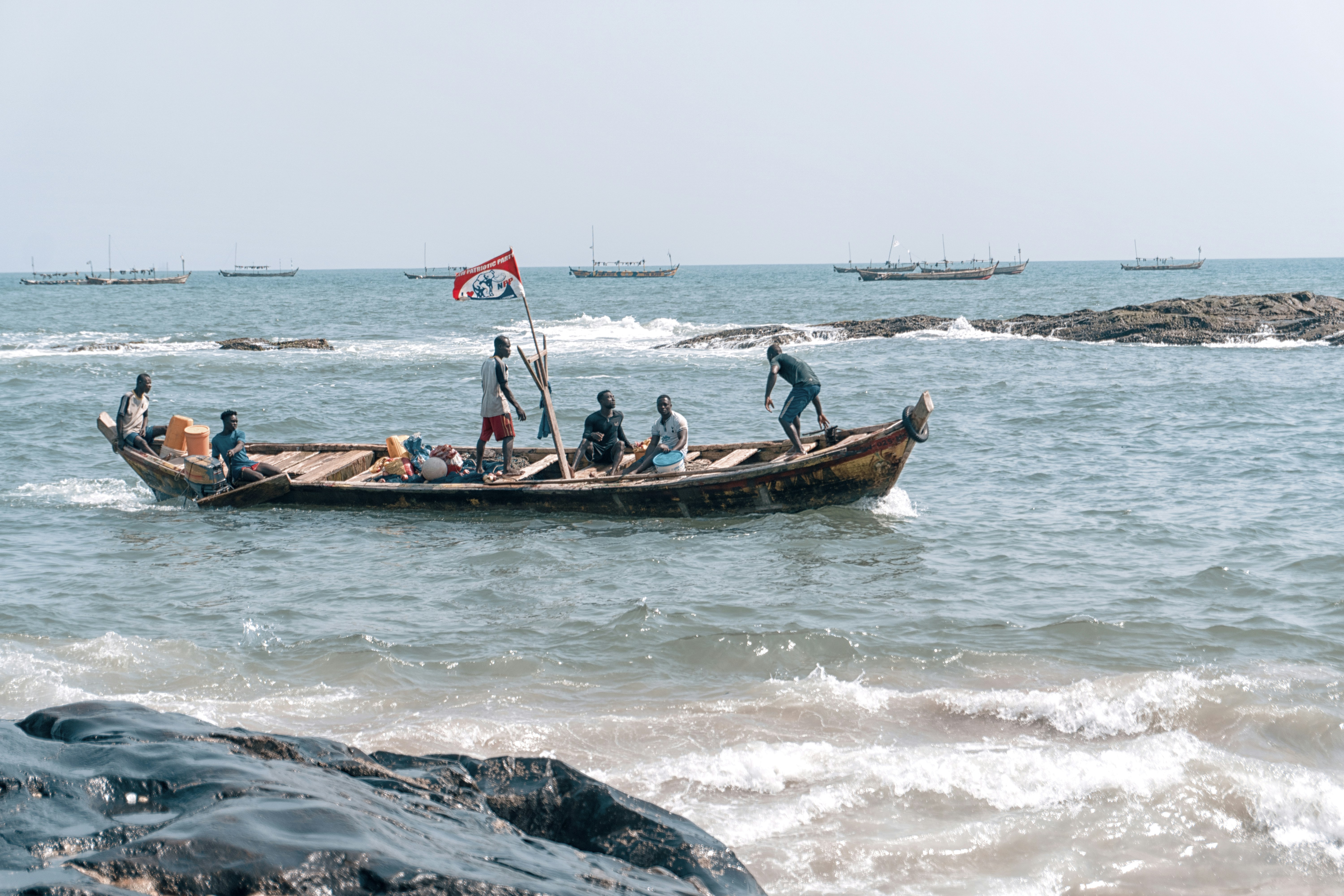 people riding boat at the ocean during day ghana teams background