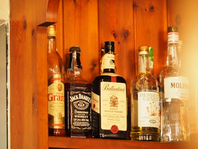 Bottles of premium vodka and rhum lined up on a wooden shelf.