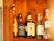 Several bottles of alcohol are lined up on a wooden shelf. Each bottle has a distinct label, indicating different types of spirits including whiskey and gin. The wood grain of the shelf adds a warm, rustic look to the image.